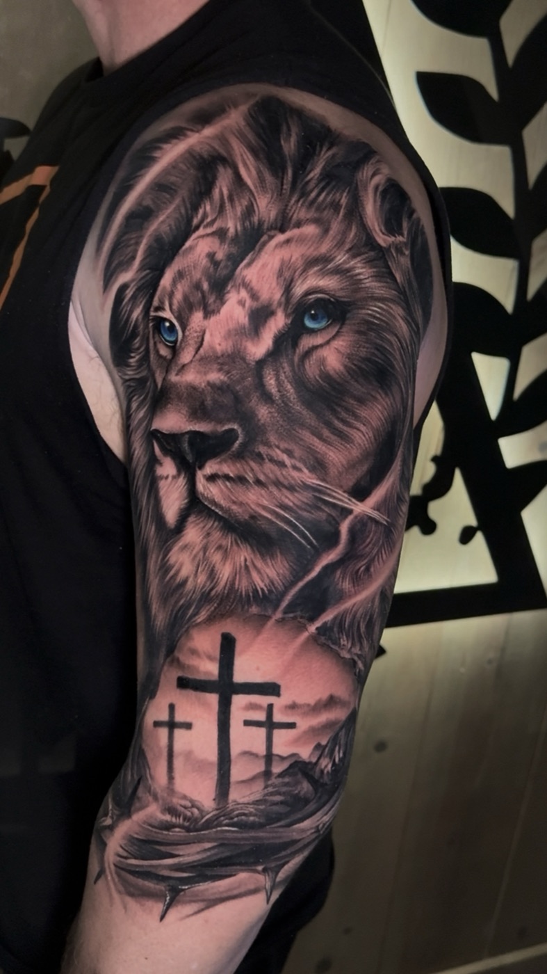 Black and grey realism lion tattoo with three crosses, half sleeve by Gerald Everfade near Sacramento